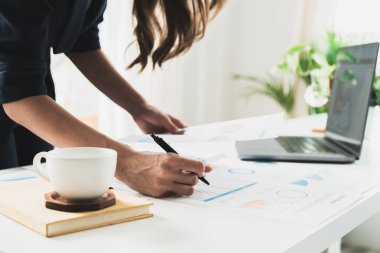 Young female accountant working with laptop and financial report in office.