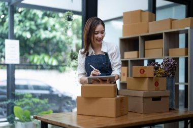 Starting small businesses SME owners female entrepreneurs Use a digital tablet to receive and review orders online to prepare to pack boxes, sell to customers, SME online business