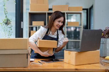 Happy business asian woman with parcel shipping box and exciting with new order. Entrepreneur small business working at home