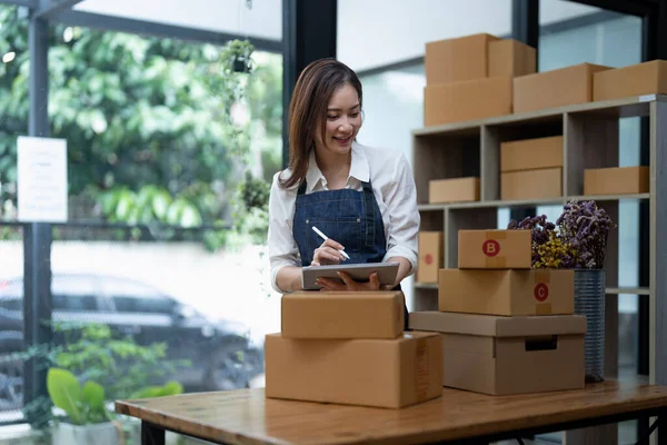 Starting small businesses SME owners female entrepreneurs Use a digital tablet to receive and review orders online to prepare to pack boxes, sell to customers, SME online business