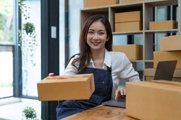 Portrait business Asian woman with parcel shipping box before send to customer. Entrepreneur small business working at home