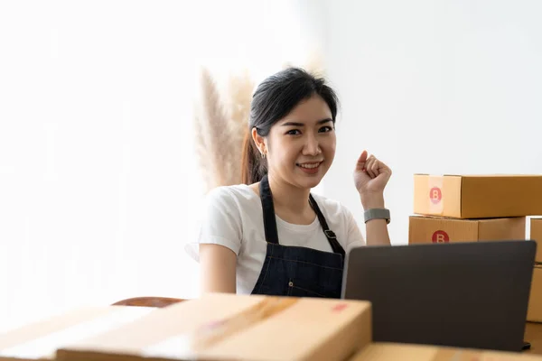 Portrait business owner smiling and feeling happy while preparing packages to ship to customers. Young woman with a lot of online orders.