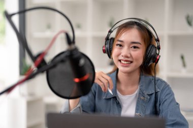 Young asian woman makes a podcast audio recording at home
