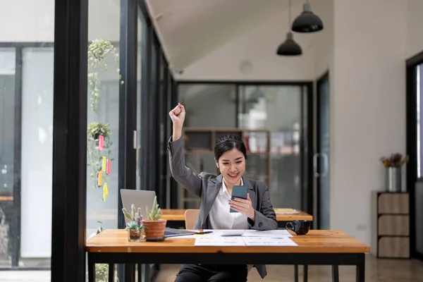 Portrait of happy young business asian woman celebrating success with arms up. positive expression, success in business concept.