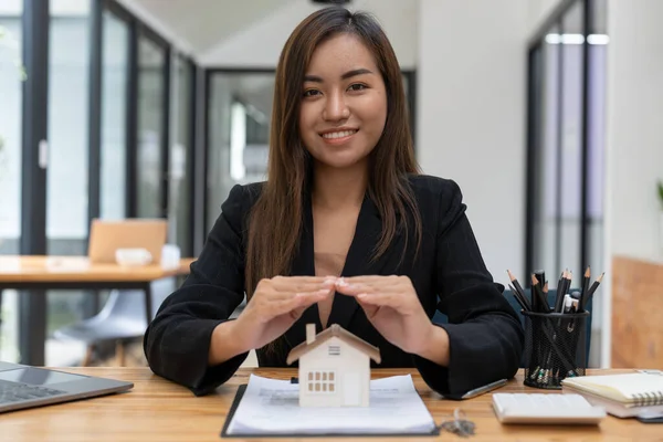Real estate concept, business woman holding a house icon. House on Hand.Property insurance and security concept. Protecting gesture of female and symbol of house