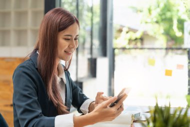 Beautiful young business woman using phone in office.