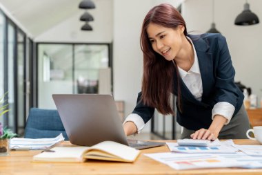 İş kadını ya da muhasebeci, iş verilerini, muhasebe belgelerini ve bilgisayarları hesaplamak için iş yerinde hesap makinesi üzerinde çalışıyor..