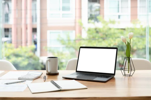 Modern office desk with open laptop computer white screen mockup, financial and marketing report, calculator and supplies