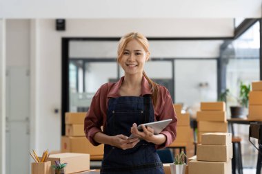 Çekici genç Asya 'lı kadın dükkan sahibinin portresi. Kameraya bakın. Evde karton kutuyla mutlu görünüyor.