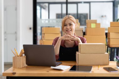 Young asian woman is entrepreneur work from home with online on notebook, online shopping, logistic and delivery, female is seller working on sofa, business SME.