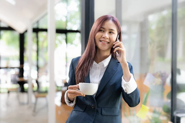 Asian female standing calling phone conversation with client and smiling