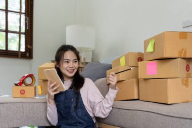 İnternet üzerinden nakliye alışverişi, iş yerindeki karton kutuya adres yazan küçük işletme sahibi gençler. Küçük işletme girişimcisi KME ya da evde kutuyla çalışan serbest çalışan Asyalı kadın.