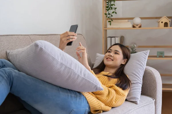 Asian Woman Holding Mobile Phone While Lying Sofa Home — Stok fotoğraf