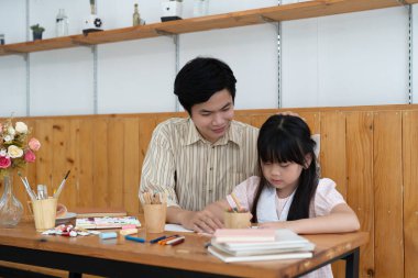 Mutlu Asyalı baba ve kızı birlikte eğleniyor, suluboya çiziyor ve boyuyor.