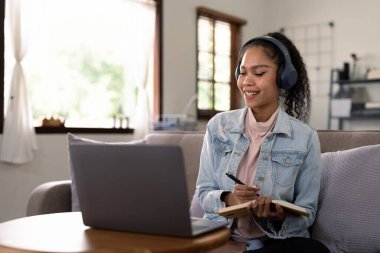 Kulaklık takan ve internetten notlar yazan melez bir kadın internet öğretmeni, bilgisayar dili öğrenen Afrikalı bir kız öğrenci..