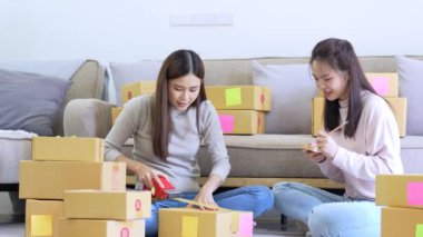 İki Asyalı kadın siparişleri topluyor. Küçük çevrimiçi işletme sahibi evde bir paket kutusu hazırlıyor. sıralama işleme ve gönderme.