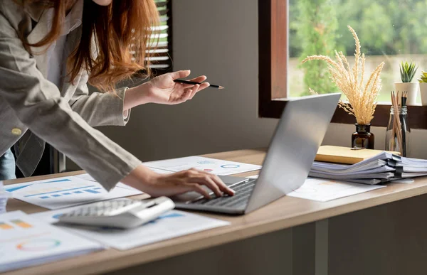 Business woman using calculator for do math finance on wooden desk in office and business working background, tax, accounting, statistics and analytic research concept.