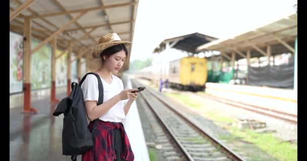 Fiatal Ázsiai Használata Mobiltelefon Barátja Várja Vonatot — Stock videók