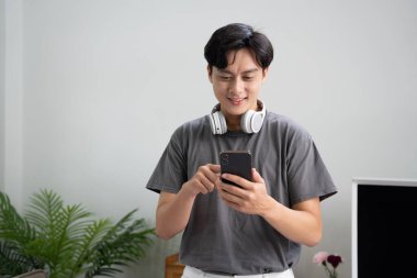 Gülümseyen adam cep telefonu kullanıyor ve kulaklıkla müzik dinliyor..