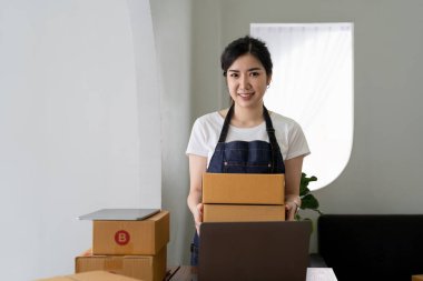 Çekici genç Asya 'lı kadın dükkan sahibinin portresi. Kameraya bakın. Evde karton kutuyla mutlu görünüyor.