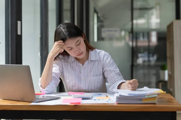 Asian woman working hard with serious stressed and headache while having a problem at work in officee, woman working hard concept