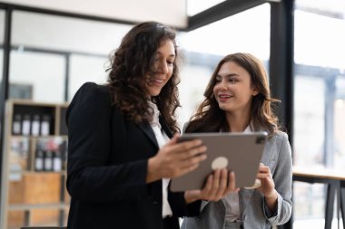 Çeşitli iş adamları birlikte çalışarak şirket mali istatistiklerini tartışıyor, çok ırklı meslektaşlar tabletteki finansman ile beyin fırtınası yapıyor