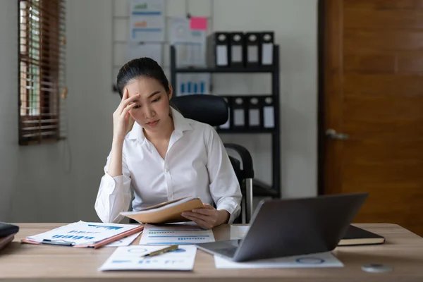 Tired asian business woman with headache at office, feeling sick at work.