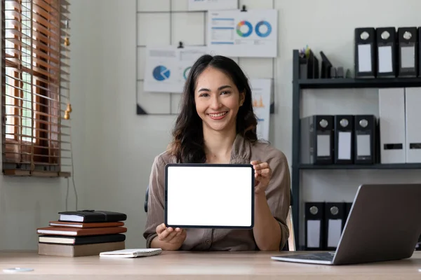 オフィスに座っている間に空白の画面を持つタブレットコンピュータを示す幸せなアジアの女性 広告のためのモックアップ — ストック写真