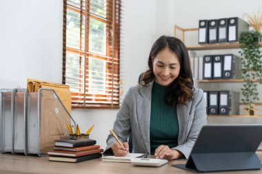 Ofisteki dizüstü bilgisayarda iş finans analizi için çalışan Asyalı kadın.