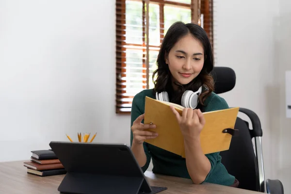 Smiling girl student wear headphone study online with laptop computer, happy young woman learn language listen lecture watch webinar write notes look at laptop sit in cafe, distant education.