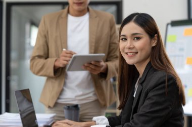 Ofiste çalışan güzel gülümseyen Asyalı kadın, kameraya bakıyor.