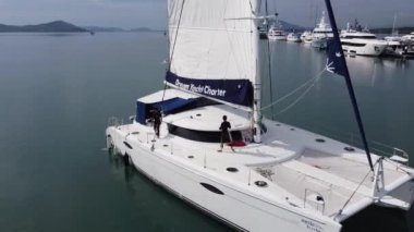 Denizci yelkenli katamaranın ana yelkeninin bütünlüğünü kontrol eder.