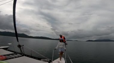 Taylandlı turistler tekne gezisi sırasında yelkenli katamaranın pruvasında poz verirler.