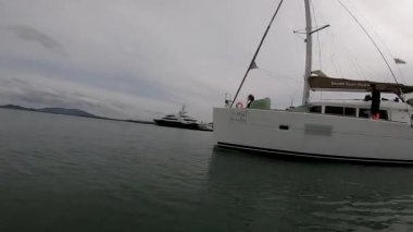 Bir motorlu tekne, bir yelkenli katamarana giden yolu geçer. Akşamları tropik bölgelerde daireler çizer.