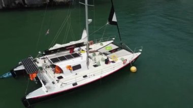 Tropikal bir adanın yakınındaki demirlemede yelken açan turistler şişme halkaların üzerinde yüzmeye hazırlanıyorlar.