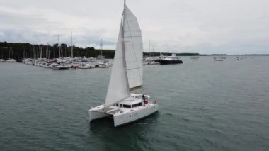 Yat limanının yanında yükseltilmiş yelkenli yelkenli yelkenli yelkenli, teknenin etrafında katamaran videosu, insansız hava aracının görüntüsü.