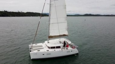 Denizci ve kaptan sırayla yelkenli katamaran körfezde, tepede.