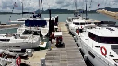 Kiralama şirketinin yöneticisi misafirleri karşılıyor ve onları tekne gezisi için yelkenli katamarana davet ediyor.