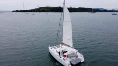 Denizci ve yelkenli katamaranın kaptanı, geminin ana yelkenini indirip, drone 'un görüş açısını düşürür.