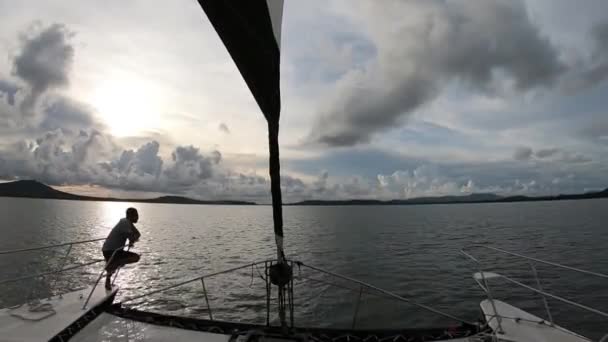航海中のカタマランの弓に座っている男の目に見えるシルエット — ストック動画