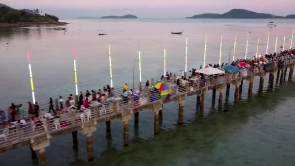 桟橋でのアジアのフェア 人々は夕方にプーケットの南のフェアで桟橋に沿って歩く ドローンからの眺め — ストック動画