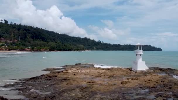 海边的灯塔在热带海的岩石上 坐着无人驾驶飞机在海滩上飞来飞去 — 图库视频影像