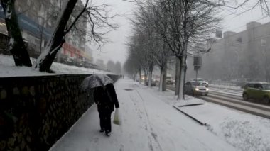 Karlı havada şemsiye altında bir kadın Rusya 'da sokakta yürüyor.