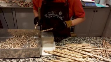 Şekerci şekerlemeleri ayırıcı bir kutuya koyar, satılık karamel şekerlemeleri hazırlar, tatlı yapar