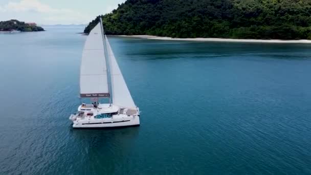 帆が開いているカタマランのセーリングは 熱帯の島の近くの海にゆっくりと浮かぶ高さからの眺め — ストック動画