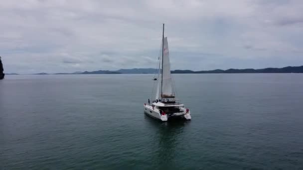 2020年9月5日タイ プーケット 熱帯の島の近くに帆の開いた白い帆船のカタマラン 船の周りのドローンビュー — ストック動画