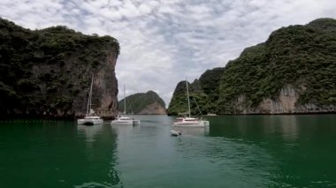 Yelkenli katamaranları, Phang Nga Körfezi 'ndeki deniz yolculuklarından sonra farklı yönlere doğru ayrılırlar.