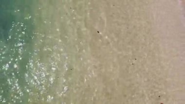İnsansız hava aracı tropikal bir plajdan kalkıyor, kumsal bir dronun gözlerinden görünüyor, yukarıdan görünüyor.