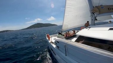Yelkenleri açık bir katamaran dalgalar arasında uçar.