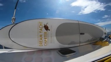 Denizdeki yelkenli bir katamaranın üzerinde SUP tahtaları var.